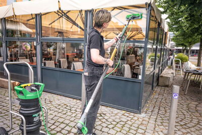 Reinigungskraft reinigt eine Glasfront am Gastropavillion.