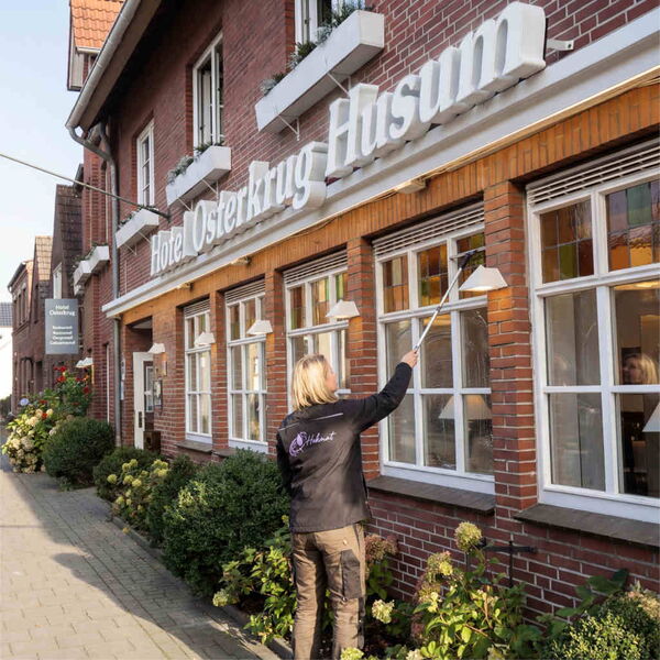 Reinigungskraft reinigt Fenster am Gebaeude.
